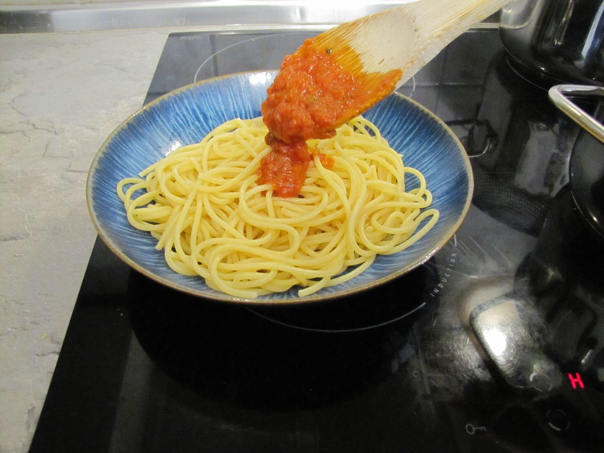 Tomatensoße auf die Spaghetti geben